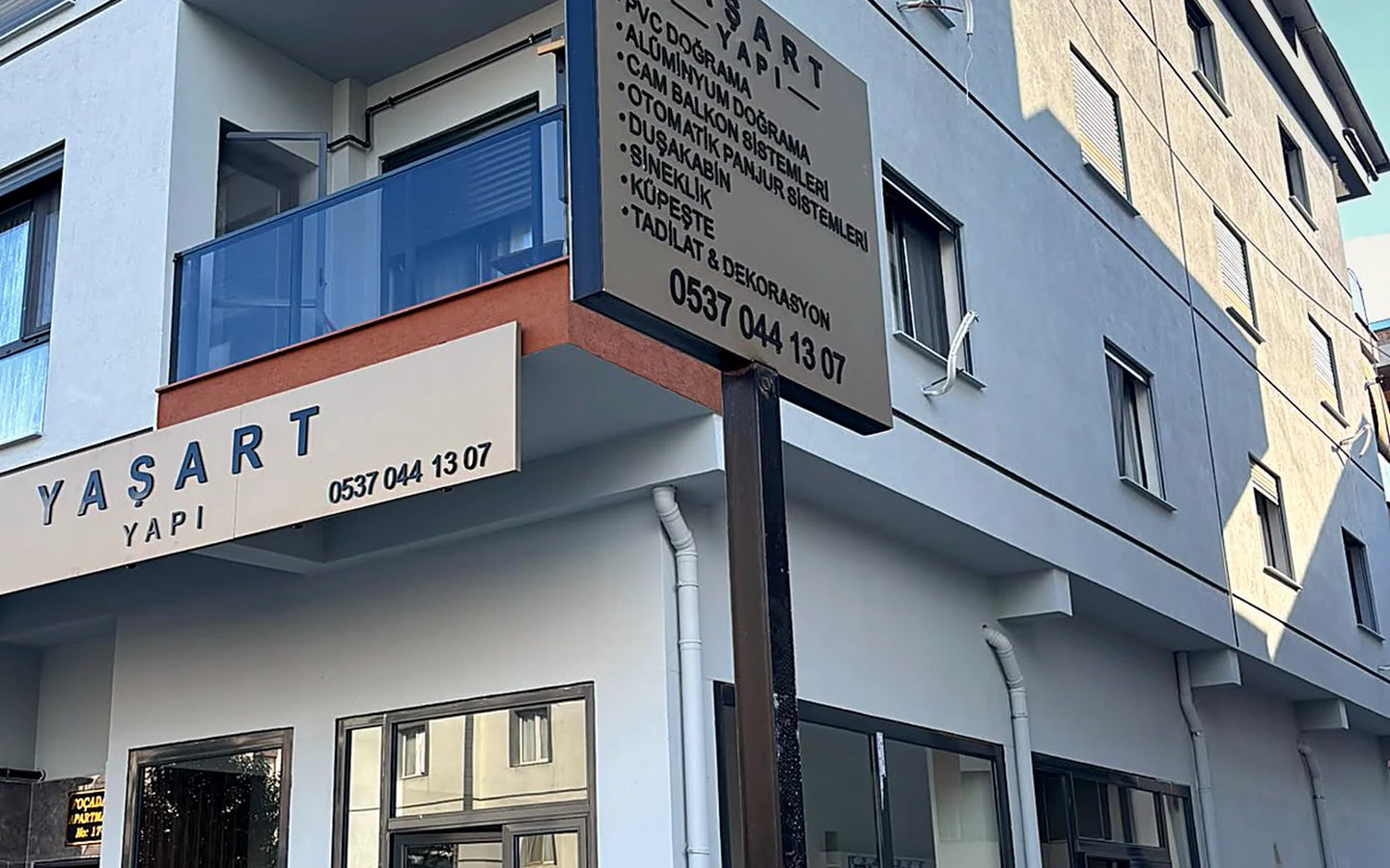 YAŞART YAPI dükkân cephesinde kutu harf tabela ve köşedeki hizmet totemi
